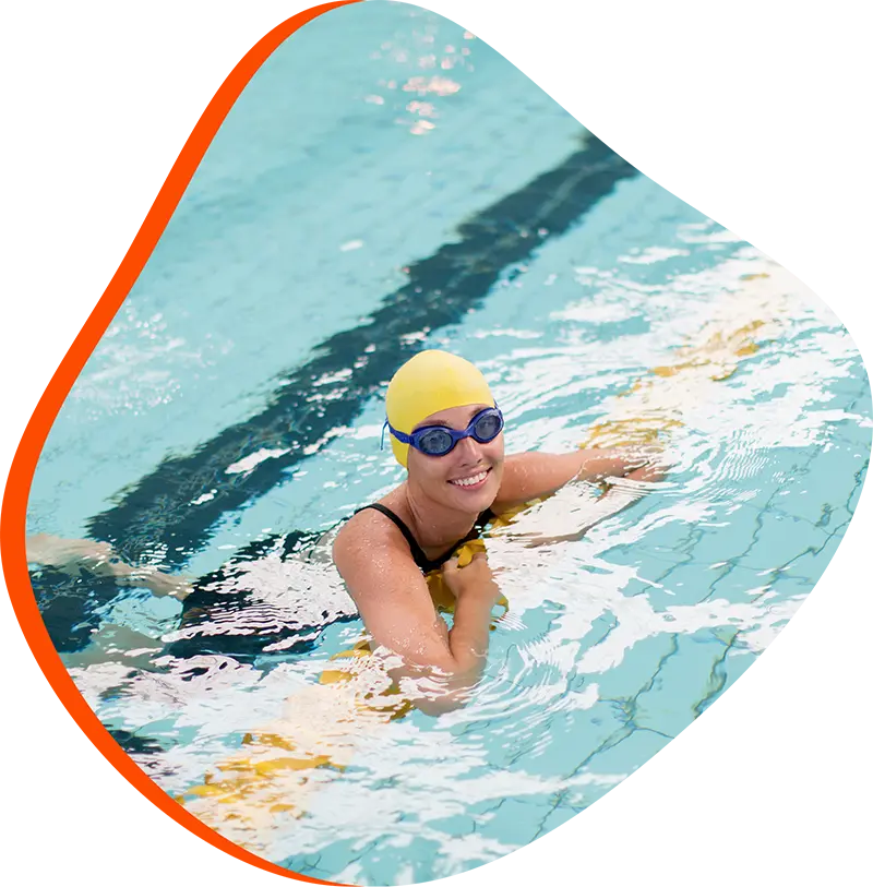 Swimmer receiving one-on-one swim instruction from a coach in an indoor pool.