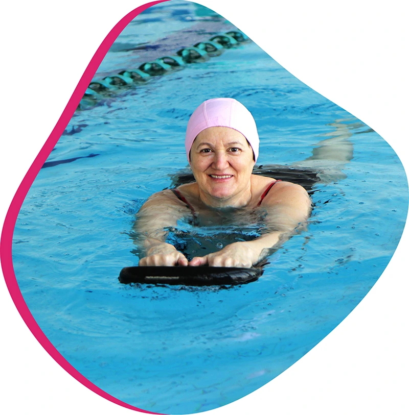 Swimmer receiving one-on-one swim instruction from a coach in an indoor pool.