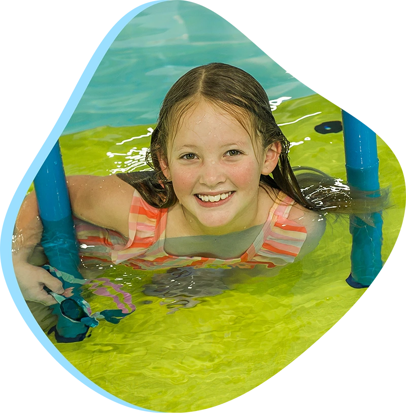 Swimmer receiving one-on-one swim instruction from a coach in an indoor pool.