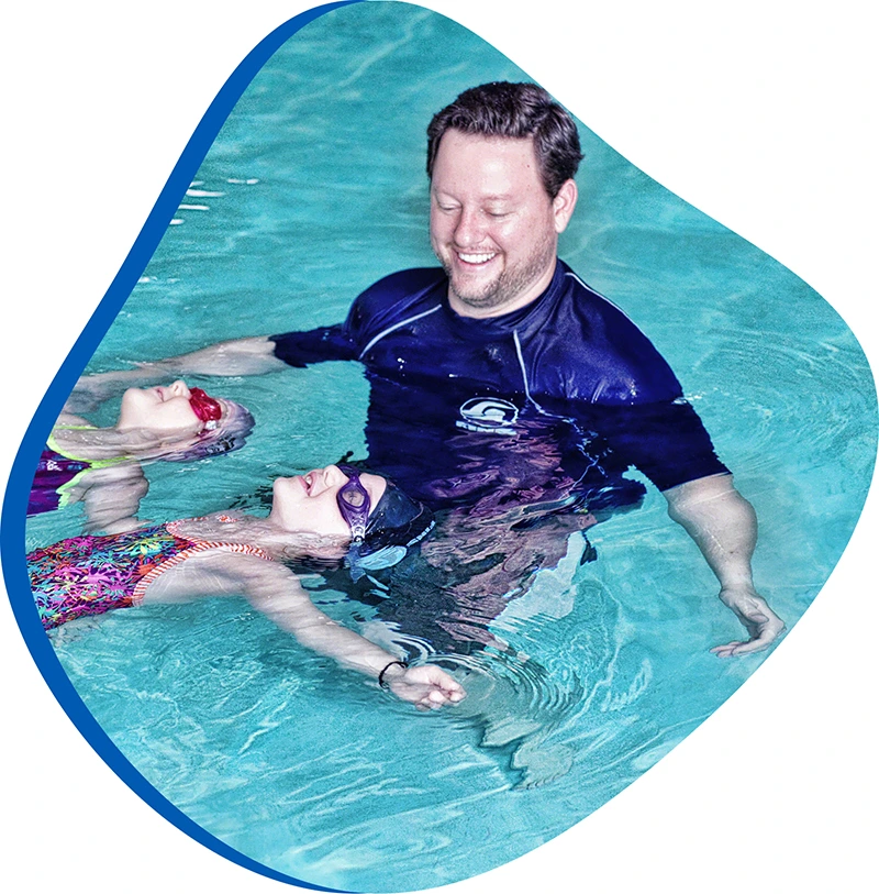 Swimmer receiving one-on-one swim instruction from a coach in an indoor pool.