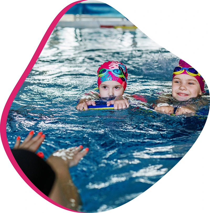 Child practicing swim techniques with an instructor in a heated indoor pool.