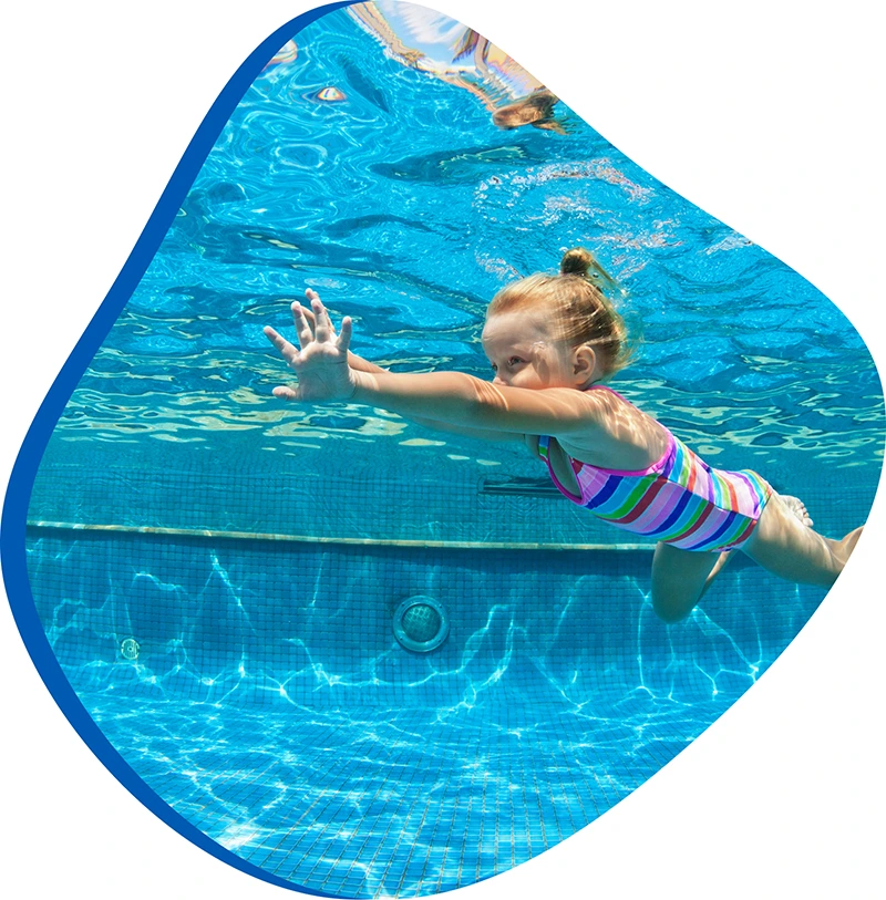 Child practicing swim techniques with an instructor in a heated indoor pool.