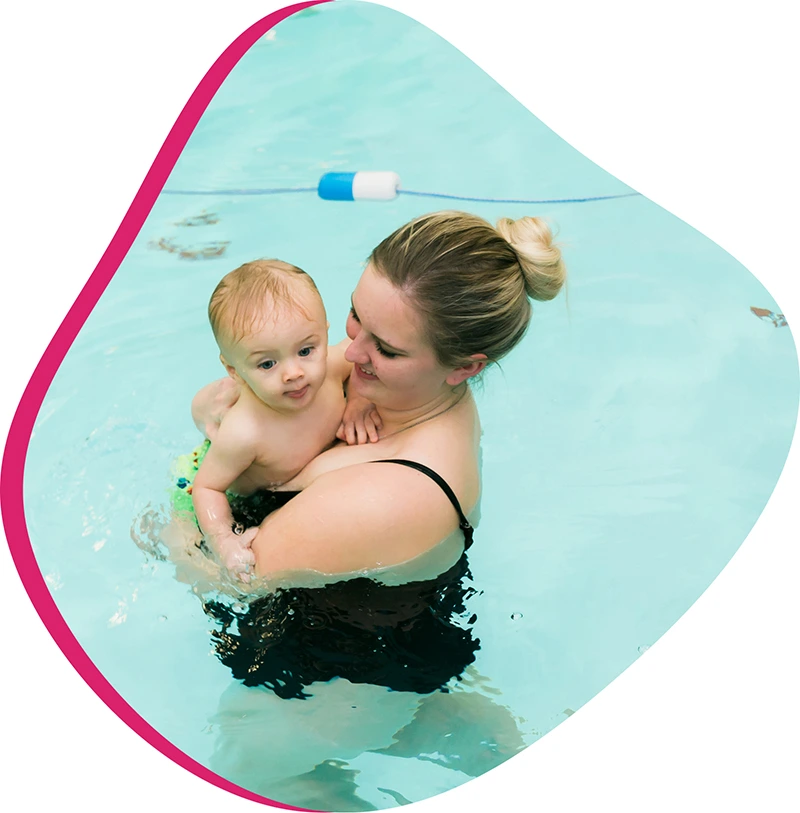 Parent helping a young child build water comfort during a swim lesson at FINS Swim School.