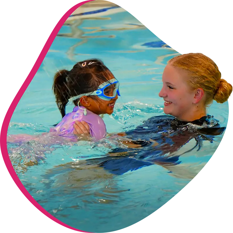 A FINS swim instructor guiding a child during a swim lesson.