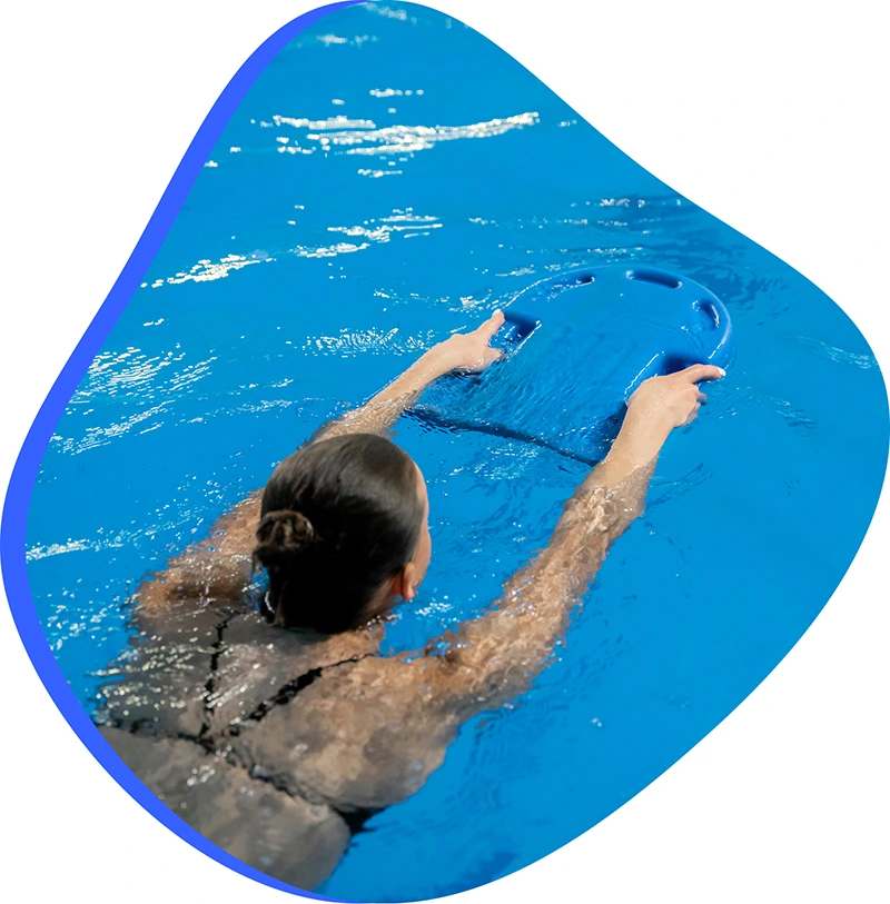 An adult student receiving personalized feedback from a swim instructor during a private session in a heated indoor pool.