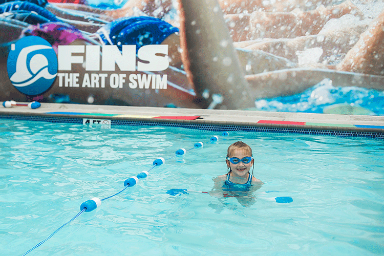 An adult student receiving personalized feedback from a swim instructor during a private session in a heated indoor pool.