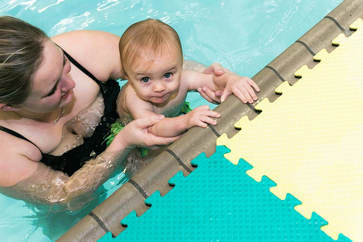 An adult student receiving personalized feedback from a swim instructor during a private session in a heated indoor pool.
