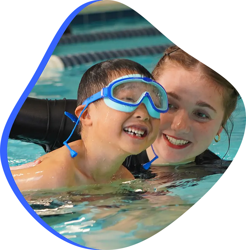 A young swimmer practicing stroke technique with a professional instructor at FINS Grand Parkway.