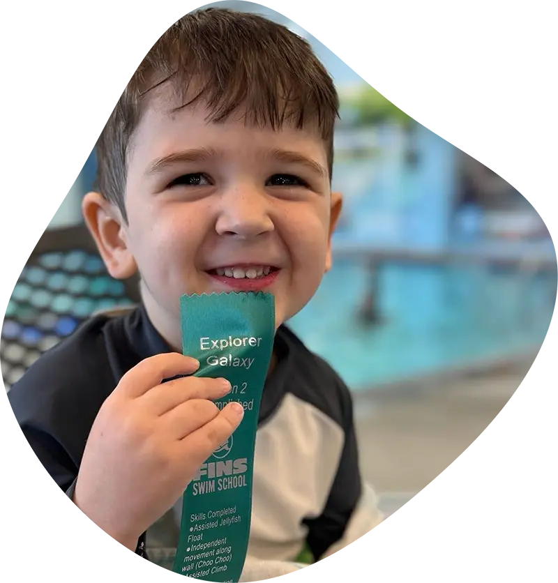 A young swimmer practicing stroke technique with a professional instructor at FINS Grand Parkway.