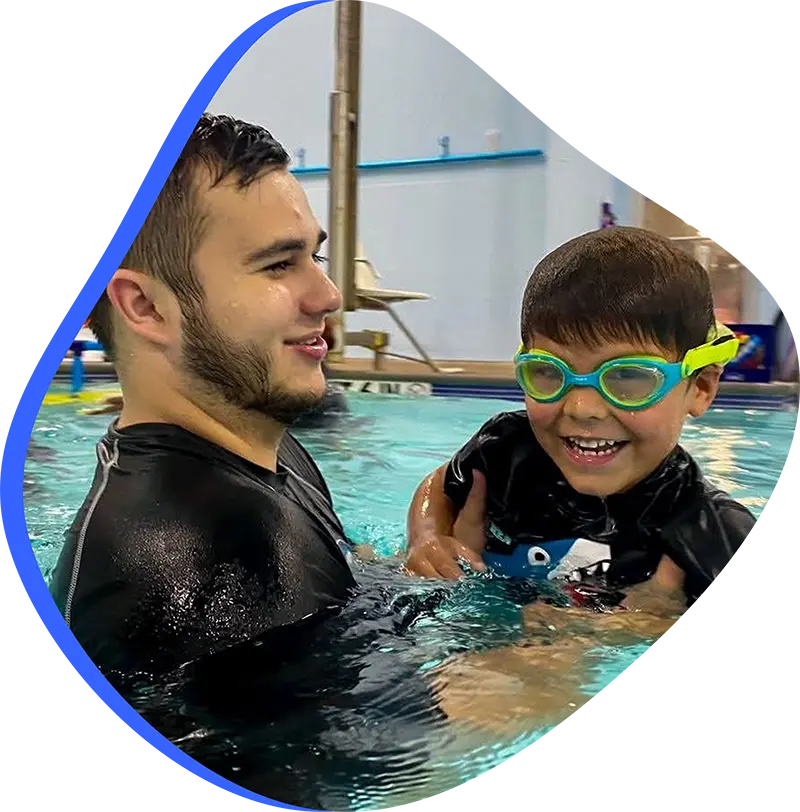 Parent assisting baby during infant swim lesson at FINS Swim School—The Woodlands indoor pool.