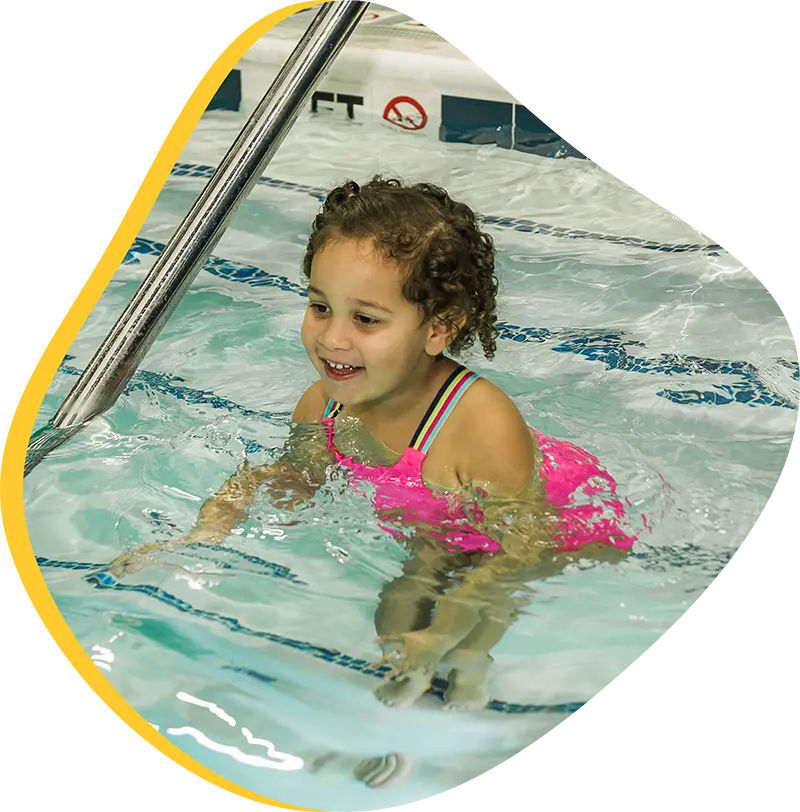 Parent assisting baby during infant swim lesson at FINS Swim School—The Woodlands indoor pool.